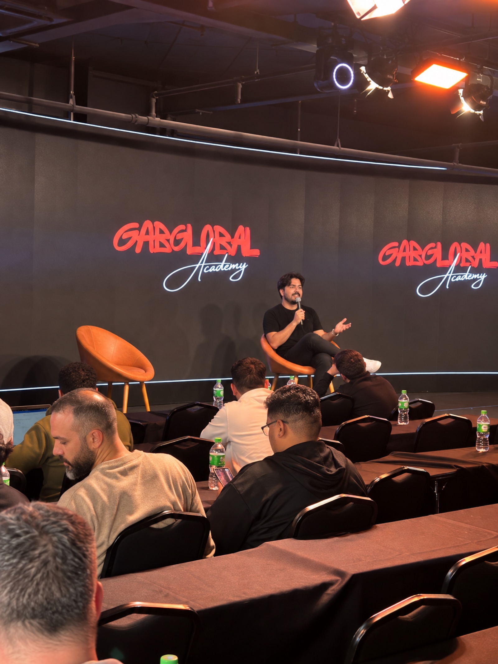 Alcides Gabriel hablando en el escenario de un evento presencial de Gab Global Academy